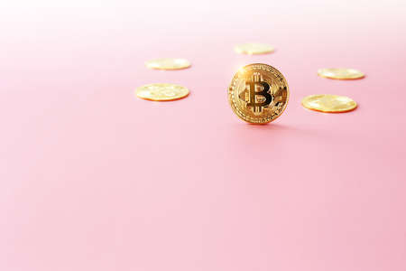 Close up golden bitcoin coin on light pink background. Cryptocurrency symbol. The shiny bitcoin gold coin stands out in front of other coins with copy space.の写真素材
