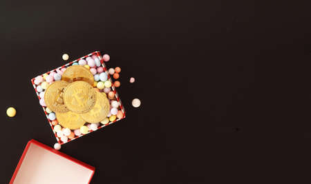 Top view of golden bitcoin in the box against black background with space. Digital currency and...