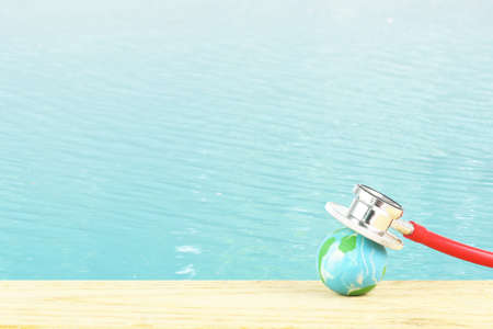 World water day , ocean day concept -  the earth on wooden table with stethoscope against water surface background. Save environmental - clean and hygiene water.の写真素材