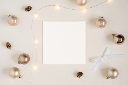 Elegant blank paper stationery photo based mockup. Festive square paper presentation for art design. Minimalist stylish banner, text template. Flat lay of card, Christmas lights, golden ornaments.の写真素材