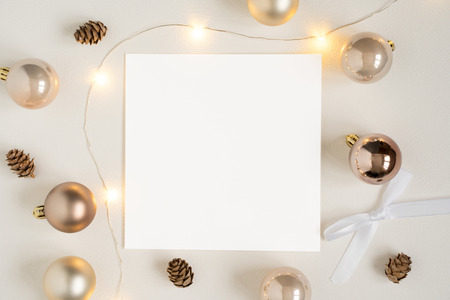Elegant blank paper stationery photo based mockup. Festive square paper presentation for art design. Minimalist stylish banner, text template. Flat lay of card, Christmas lights, golden ornaments.の写真素材