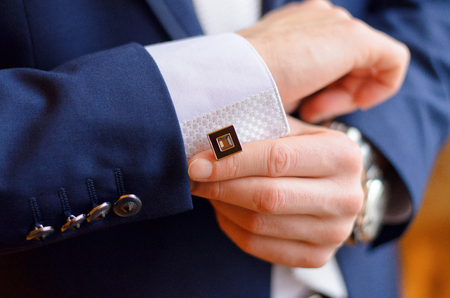 a man fastens a cuff-link on a cuff