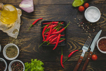 Red chili peppers, whole and cut, on a wooden background.