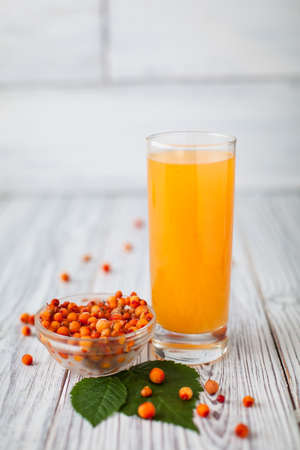 Sea- buckthorn juice , glasss, leaves  plate  woodenの写真素材