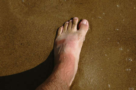 Man's legs on the sand beach and sea wavesの写真素材