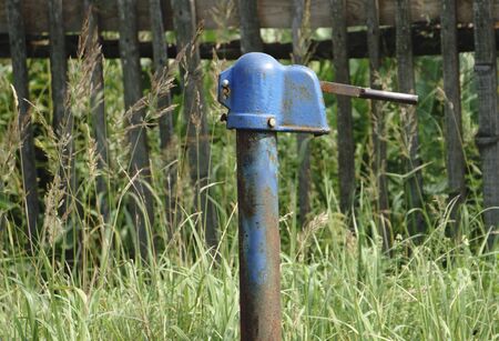 Water pump against a blockhouse in the villageの写真素材
