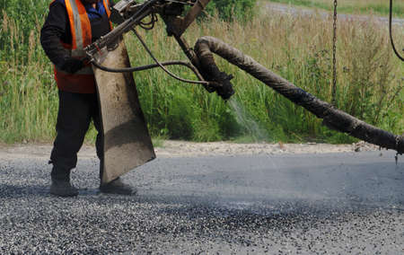 Close view on the worker and the asphalting machinesの写真素材