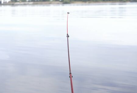 fishing rod and reel on the summer lakeの写真素材