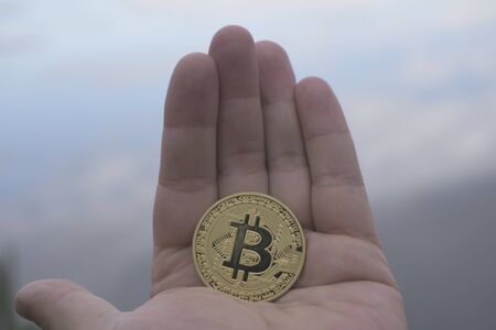 hand man holding a gold Bitcoin in the backgroundの写真素材