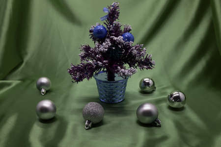 A small Christmas tree in a pot, decorated with balls, garlands and lights.の写真素材