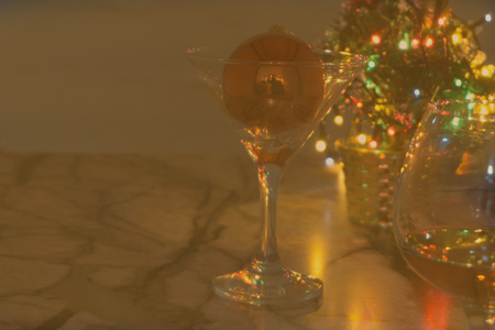glass with cognac or whiskey, gift box, colored balls and christmas tree on wooden table