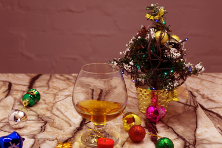 Glass with drink, a Christmas ball and tinsel on a black background. Glass with alcohol and a...