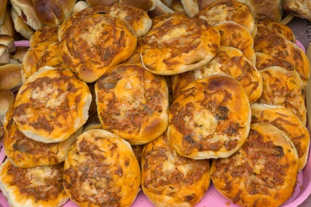 Mini-pizzas heaped on a wooden Board background
