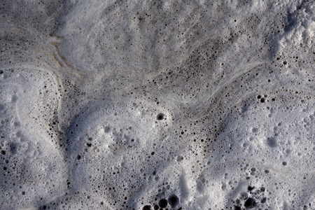 white foam on water and waves background texture, gray river froth, cumulus airy sea lake foam, foam on the water with bubbles, foam aggregates, close-up, macro, lather .の写真素材