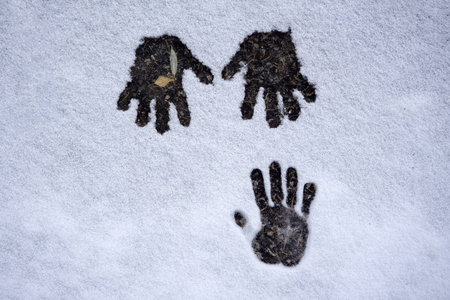 three hands prints in the snow background winter time seasonの写真素材