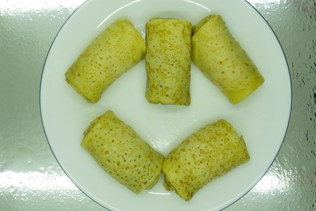 Homemade pancakes stuffed, wrapped with an envelope on a white plate, traditional food on a pancake...