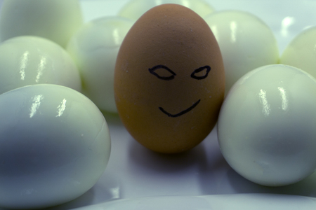 eight brown eggs with faces drawn arranged in cartonの写真素材