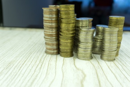 Stacks of coins on white background different heights, reducing the income of the business