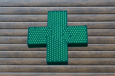 Neon green cross sign on wooden background .の写真素材