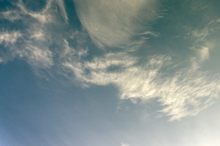 rose colored lens showcases clouds passing on front of morning sunの写真素材
