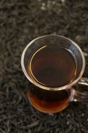 a few tea leaves on a blurred pile of dry tea leaves background, large leaf black Bayh tea front view, short focus. on whiteの写真素材