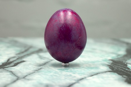 Easter Eggs on green and yellow geometric background. Burgundy egg handmade new style of colouring on a colored cardboard. Pattern, easter concept.Flat, top view of egg, geometric backgroundの写真素材