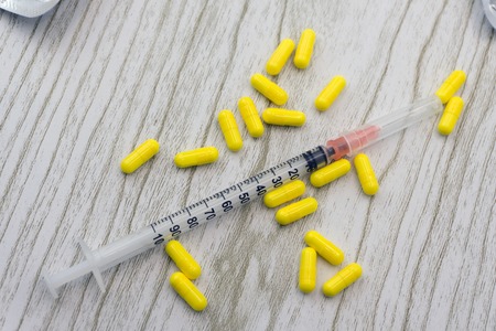 Medication colorful round tablets, capsule, pills arranged abstract on yellow background. Aspirin, ampoule, empty syringe needle. Health, treatment, choice, healthy lifestyle concept. Copy spaceの写真素材