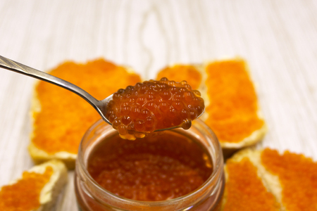 Sandwiches with imitation red caviar and butter close-up on wooden cutting board on wooden tableの写真素材