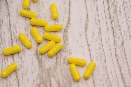 closeup of pills or capsules with over yellow backgroundの写真素材