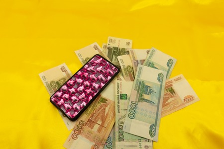 euro coins, paper money and mobile phone on a yellow background .
