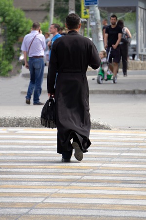 Full length portrait of mature reverend in black mantle with open hands isolated on white backgroundの写真素材