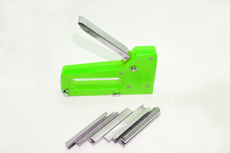 the hand of the worker uses an steel industrial stapler. industrial stapler nailing the leather to...