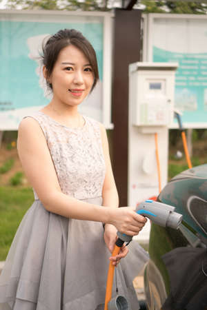 A women holding a charge nozzle about to charge a carの写真素材