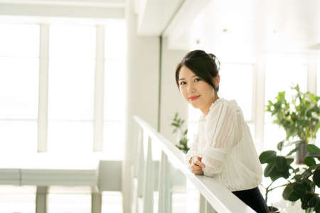 office lady standing leaning on a fenceの写真素材