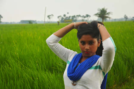 Close up of a teenage girl wearing white salwar and blue dhupatta with long hairs standing in a...