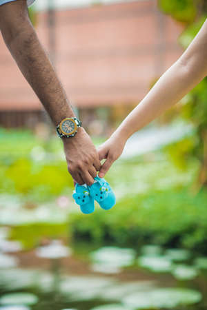 the hands of the couple carrying the baby shoes