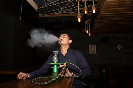 A man smoking hukka and exhaling smoke from monthの写真素材