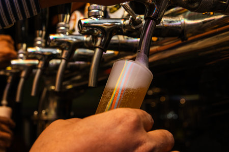 Bartender pouring beer from the tap in a pub. Selective focus.の写真素材