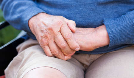 Old man sitting in wheelchair, warming up his hands 