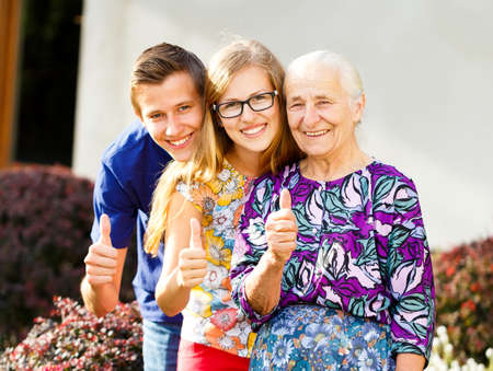 Kind grandmother showing thumbs up with grandchildren.