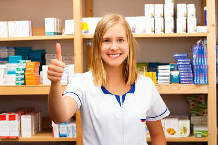 Kind young pharmacist showing confident thumbs up.の写真素材