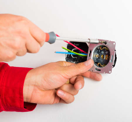 Electrician assembling new electrical outlet on wall.