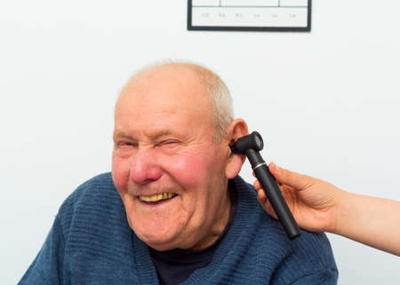 Happy patient at the otolaryngology, making fun with doctor during examination with auroscope.
