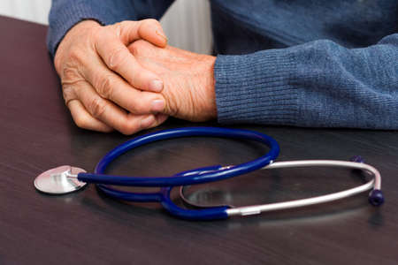 Elderly health care concept - old hands  laying near a stethoscope.の写真素材