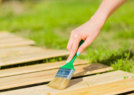Woman hand with positive grained nails applying flax oil on plank.の写真素材