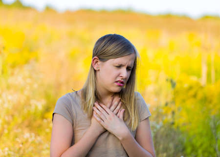 Sick woman with asthmatic allergy symptom because of rapseed on the field.