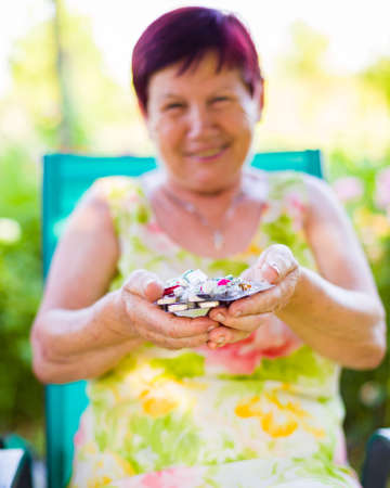 Close-up of an elderly woman holding her medicines outdoor.