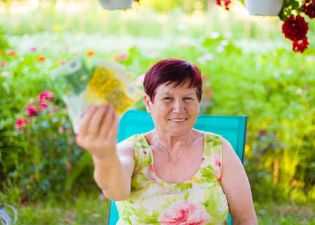 Portrait of proud pensioner woman holding her saved money.の写真素材