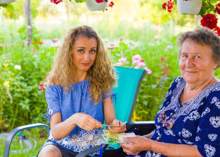 Daughter giving money as birthay present for retired mother in rehabilitation.の写真素材