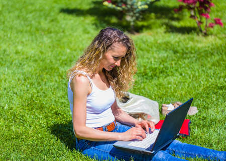 Busy female studen studying before session exams from laptop courses in the park.の写真素材